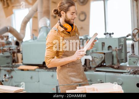 Ein Zimmermann arbeitet an einer Holzbearbeitungsmaschine, der den Schneider in der Werkstatt hält Stockfoto