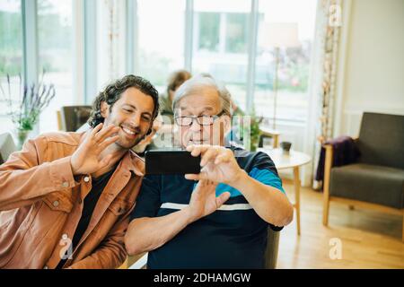 Senior man und Enkel Videokonferenzen auf Smartphone bei Altersheim Stockfoto