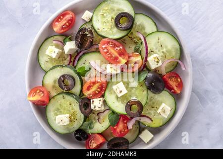 Griechischer Salat, ein Foto von oben. Frischer Salat mit Feta, Tomaten, Gurken, Zwiebeln und Oliven Stockfoto