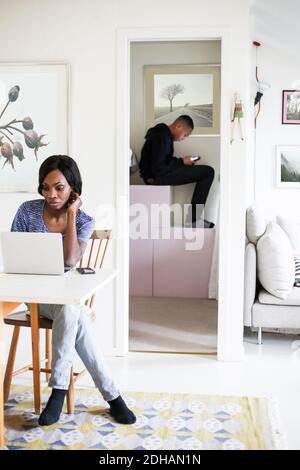 Mittlere Erwachsene Frau mit Laptop am Tisch mit Sohn sitzen Im Lagerraum Stockfoto