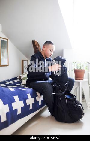 Teenage boy packen Kleidung in Rucksack im Schlafzimmer zu Hause Stockfoto