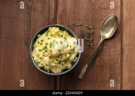 Pomme Püree, ein Foto über dem Kopf von einer Schüssel Kartoffelpüree mit Kräutern, von oben auf einem rustikalen Hintergrund mit einem Zweig von geschossen Stockfoto