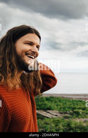 Nahaufnahme eines lächelnden Mannes mit langen Haaren am Strand Stockfoto