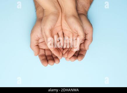 Zwei weibliche Hände liegen in männlichen Handflächen auf einem blauen Hintergrund Stockfoto