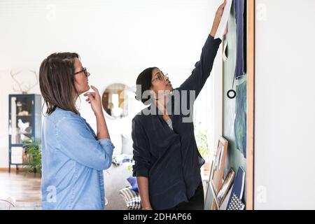 Weibliche Design-Profis diskutieren über Gemälde auf Tafel in zu Hause Büro Stockfoto
