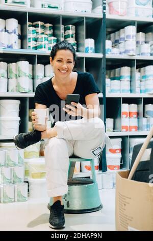 In voller Länge Porträt der Verkauf Frau sitzt auf Hocker in Lagerraum Stockfoto