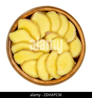 Frische Ingwerscheiben in einer Holzschüssel. Rhizome von Zingiber officinale, in Abschnitte geschnitten, als duftendes Gewürz und als Volksmedizin verwendet. Stockfoto