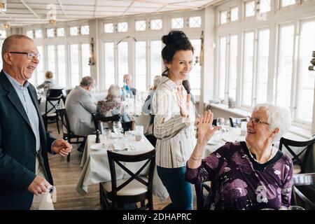 Ältere Freunde geben High-Five im Restaurant Stockfoto