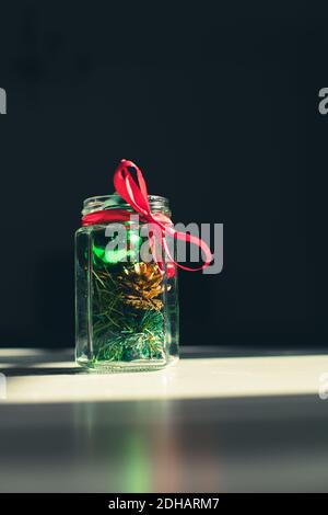 Weihnachtsdekorationen in einem Glas auf Tisch mit Band Stockfoto