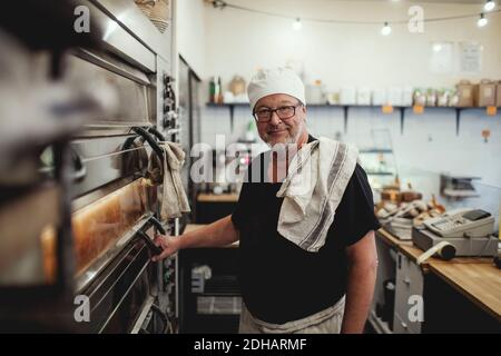 Portrait eines älteren Bäckers, der beim Ofen in der Bäckerei steht Stockfoto