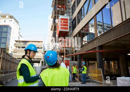 Architektinnen in reflektierender Kleidung diskutieren auf der Baustelle Stockfoto