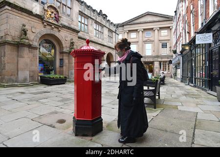 Frau postet einen Brief in einem viktorianischen sechseckigen Briefkasten in Shrewsbury, Großbritannien. Eines von nur 50 hergestellt wurden sie von I.W. entworfen Penfold und hergestellt von C Stockfoto