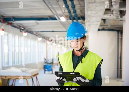 Selbstbewusste Ingenieurin in reflektierender Kleidung mit digitalem Tablet AT Baustelle Stockfoto