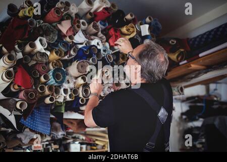 Low-Winkel-Ansicht von älteren männlichen Besitzer Blick auf gerollt Stoffe in der Werkstatt Stockfoto