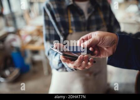 Zugeschnittenes Bild des Kunden, der mit Kreditkarte an die Frau zahlt Handwerker Stockfoto