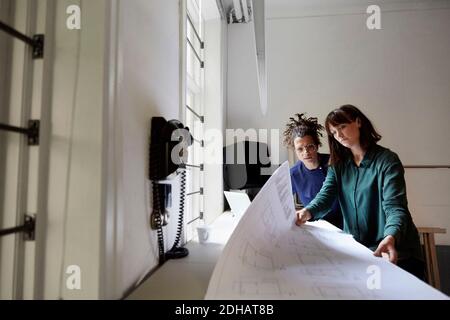 Architektin mit Blaupause am Tisch im Büro Stockfoto