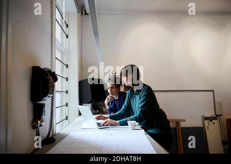 Architektin diskutiert über Laptop am Tisch im Büro Stockfoto