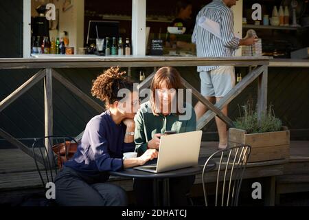 Architektinnen diskutieren über das Handy im Café im Freien Stockfoto