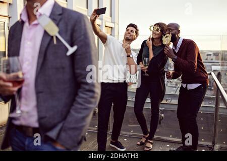 Office-Freunde mit Requisiten machen Selfie, während sie Getränke genießen Party auf der Terrasse Stockfoto