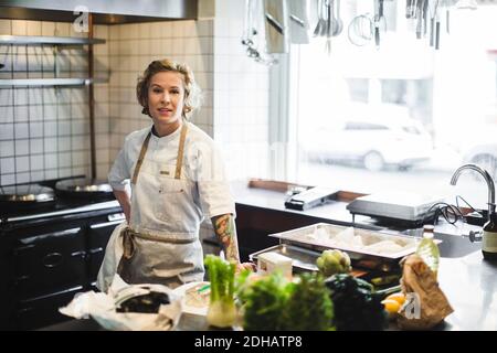 Portrait der selbstbewussten weiblichen Besitzerin, die an der Küchentheke steht Restaurant Stockfoto