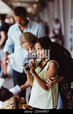 Glückliche Mutter und Tochter beim Betrachen der Kamera, während sie dabeistehen Familie am Bahnhof Stockfoto