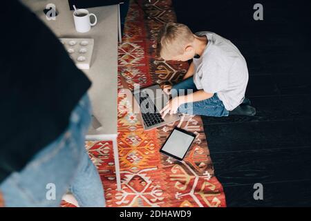 High-Angle-Ansicht des Jungen mit Laptop am Couchtisch Im Wohnzimmer zu Hause Stockfoto