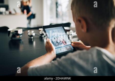 Rückansicht des Jungen mit digitalem Tablet zu Hause Stockfoto