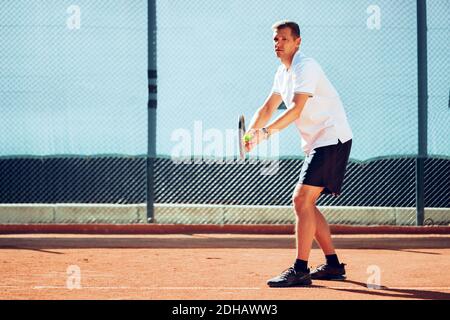 Junger professioneller Tennisspieler, der einen Service leistet Stockfoto