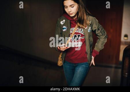 Mädchen mit Smartphone, während zu Fuß auf Treppen in der Wohnung Stockfoto