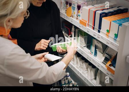 Ansicht von älteren Kunden und weiblichen Besitzern Medikamente per Regal in der Apotheke Stockfoto