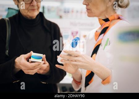 Mittelteil des Senior-Kunden und der weiblichen Besitzerin, die Medikamente bei hält Apotheke Stockfoto