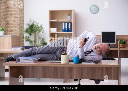 Alter männlicher Mitarbeiter, der am Arbeitsplatz an einer Radikulitis leidet Stockfoto