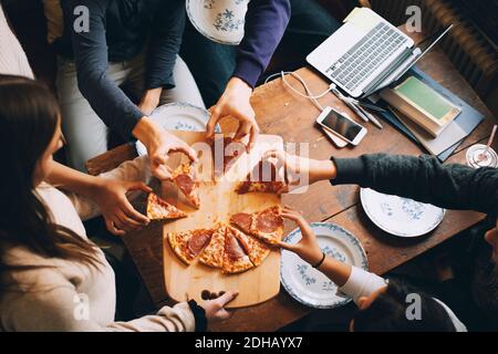 Man hat einen Blick auf Freunde, die Pizza nehmen Esstisch Stockfoto