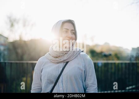 Hinterleuchtet von lächelnder junger muslimischer Frau, gegen die Hijab getragen wurde Himmel Stockfoto