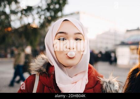 Portrait einer jungen muslimischen Frau, die in der Stadt Kaugummi bläst Stockfoto