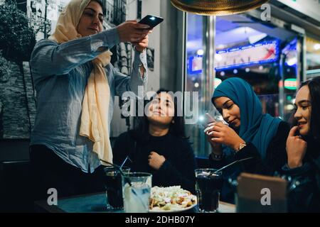 Junge muslimische Frauen fotografieren Essen und Getränke auf dem Tisch mit Freunde im Café Stockfoto