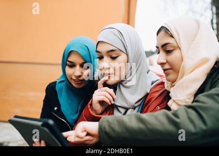 Junge muslimische Freundinnen teilen sich digitale Tablets in der Stadt Stockfoto