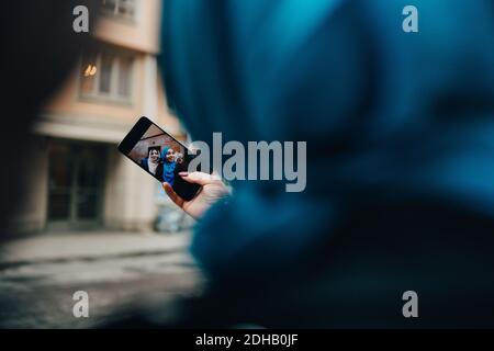 Zugeschnittenes Bild einer Frau, die mit einem Freund in der Stadt Selfie gemacht hat Stockfoto