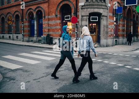 Die ganze Länge der lächelnden jungen muslimischen Frauen, die auf der Straße gehen In der Stadt Stockfoto