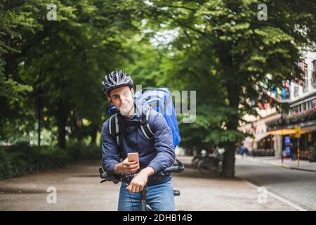 Porträt von selbstbewussten Lebensmittel Lieferer mit Fahrrad in der Stadt Stockfoto