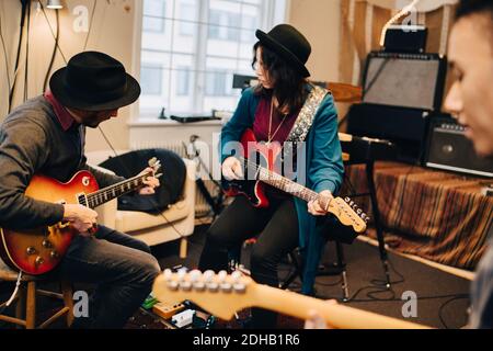 Männliche und weibliche Freunde spielen Gitarre, während sie beim Aufnehmen üben studio Stockfoto