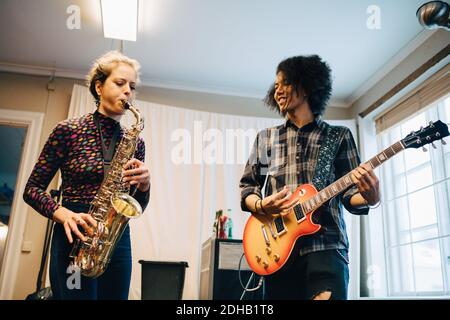 Freunde spielen Saxophon und Gitarre beim Üben im Aufnahmestudio Stockfoto