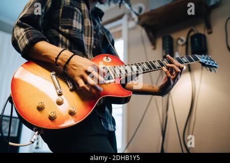 Mittelteil des Mannes, der Gitarre spielt, während er im Aufnahmestudio trainiert Stockfoto