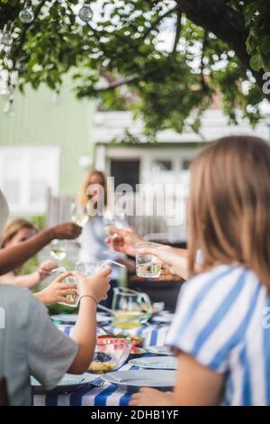 Kinder toasten Trinkgläser, während sie mit der Familie beim Essen sitzen Tisch im Hinterhof Party Stockfoto
