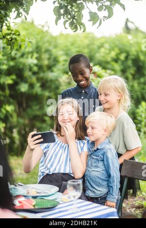 Mädchen, die Selfie mit Freunden auf Handy im Hinterhof Stockfoto