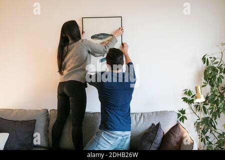 Paar hängen Gemälde während lehnte sich auf Sofa zu Hause Stockfoto