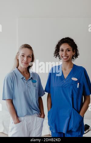Portrait einer selbstbewussten Krankenschwester und Ärztin, die gegen Weiß steht Wand im Krankenhaus Stockfoto