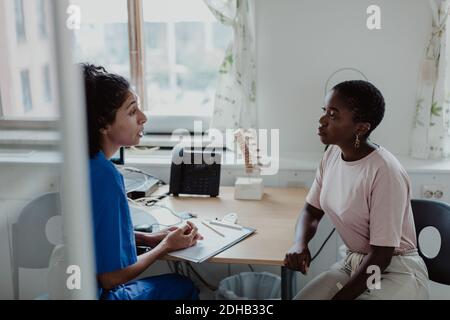 Weibliche Angestellte im Gesundheitswesen, die den jungen Patienten medizinische Unterlagen erklärt Büro Stockfoto