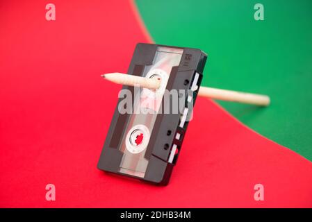 Vintage-Audiokassette mit Magnetband und Holzstift auf Roter und grüner Hintergrund Stockfoto