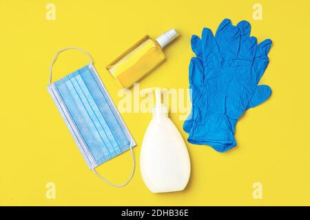 Gesichtsmaske, Handschuhe, Seife und Desinfektionsmittel auf hellem gelben Hintergrund Stockfoto